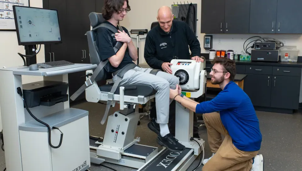 Two A T students practice using a Biodex machine