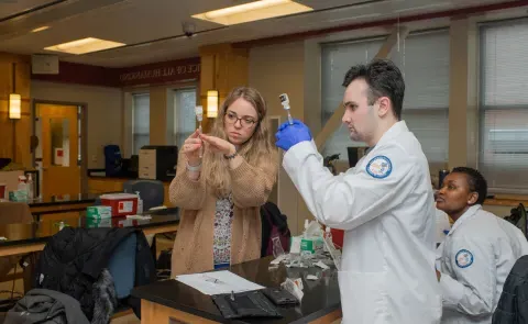 UNE pharmacy students draw vaccines from vials in a lab setting